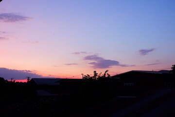 Photograph of the silhouette of a house roof under a sky of orange-red clouds on a winter evening in December.