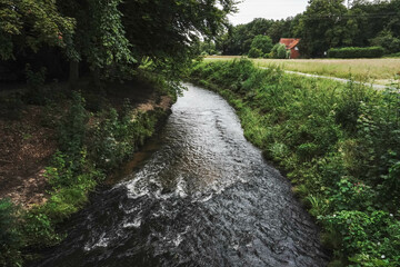 A park with a river gently winding through greenery and trees