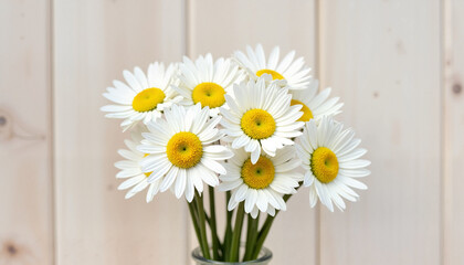 Obraz premium Bouquet of fresh daisies in a glass vase against a light wooden background, creating a cheerful ambiance