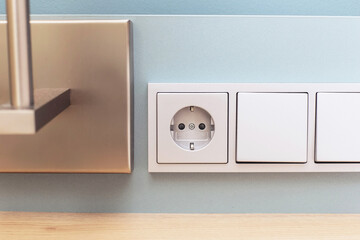 Electrical socket closeup. Hotel room with bedside electric outlet and light controls. Wall light...