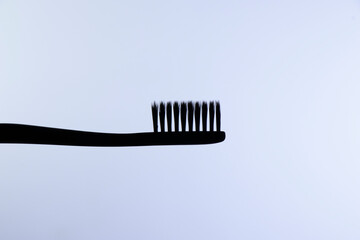 Black toothbrush with black bristles close-up on a gradient white background
