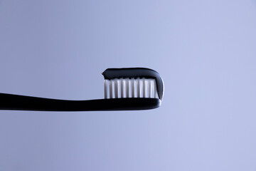 Black-white toothpaste on a Black toothbrush with White bristles close-up on a gradient white-gray background