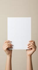 Female hands hold a blank sheet of paper on a beige background. Advertising space