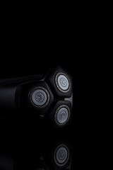 Closeup Image of 3 Blades Electric Shaver On Black Reflective Surface. Vertical image Composition