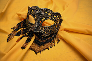 Venetian mask with beads lying on golden fabric is waiting for the carnival party