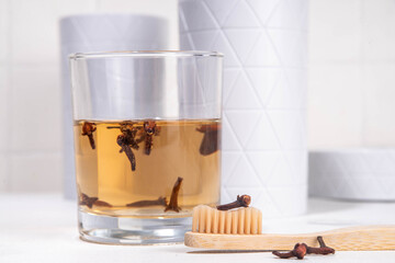 Clove Mouthwash with toothbrush on white table