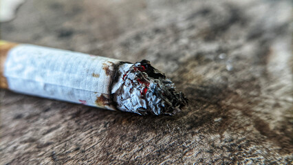 Selective focus or close-up of a burning cigarette on a wooden table.
