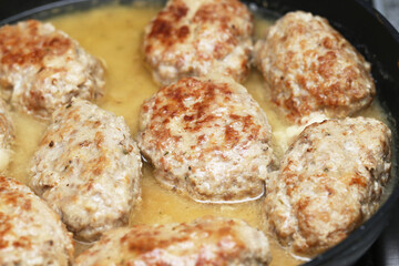 Fototapeta premium Frying meat patties on a pan. Homemade pork cutlets cooking. Traditional minced meat dish preparation. Juicy meatballs sizzling on the stove. Delicious dinner idea with golden brown chops.