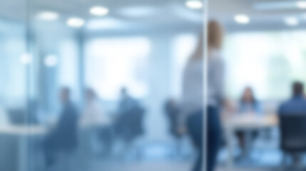 A blurred office background for a presenter, with light grey tones, bright lights, and people working