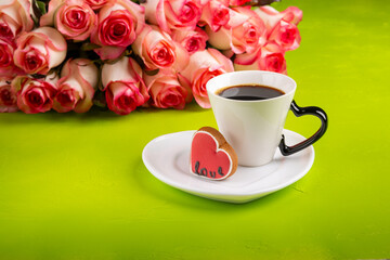 Cup of coffee, heart-shaped cookies and a bouquet of roses on green background. Valentine's day concept