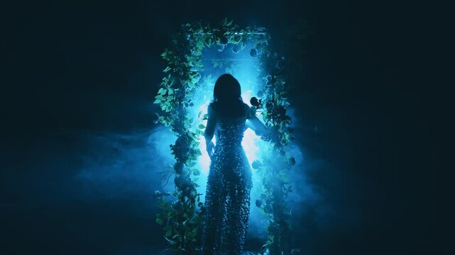 dark shadow mysterious silhouette fantasy woman walking in black night garden in fog fairytale portal arch flowers, art neon blue magic light. Mystery lady Gothic Girl princess in smoke back rear view