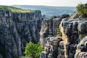 A breathtaking view of a rugged canyon landscape with towering cliffs and lush greenery against the...