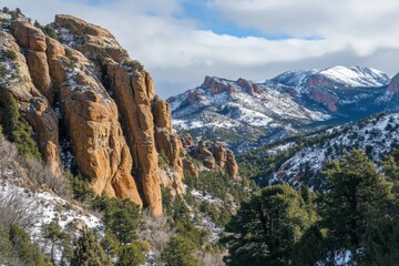 Obraz premium A stunning view showcasing rugged rocky mountains with patches of snow and lush green pine trees, capturing the essence and beauty of winter in the wilderness.