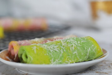 a close up of pancake rolls or Dadar Gulung with a rainbow pattern ready to be served. Food concept photo. Indonesian traditional food.