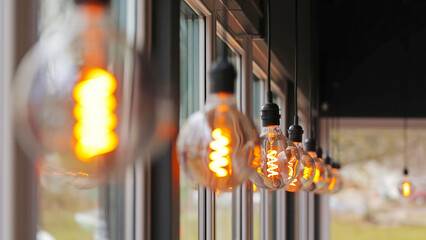 Row of Vintage Edison Bulbs in Window. Close-up of glowing vintage Edison light bulbs with spiral...