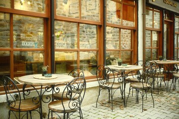 Safranbolu, Karabük, Türkiye - November 28, 2024: an outdoor vintage café exterior with wrought iron chairs and rustic wooden window in an urban area