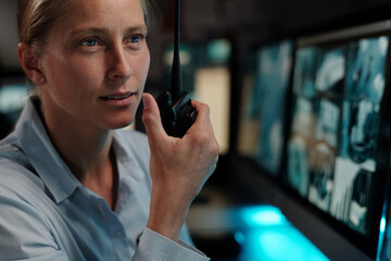 Young officer in uniform looking at computer screen with cctv video and reporting situation on...