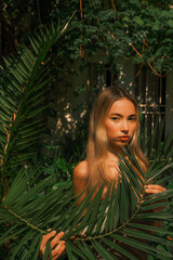 A woman is posing in front of a tree with leaves
