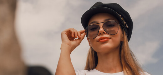 A woman wearing sunglasses and a hat is smiling