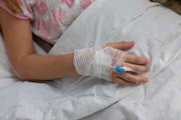 A childs hand is seen with an IV in a hospital setting, illustrating medical care efforts