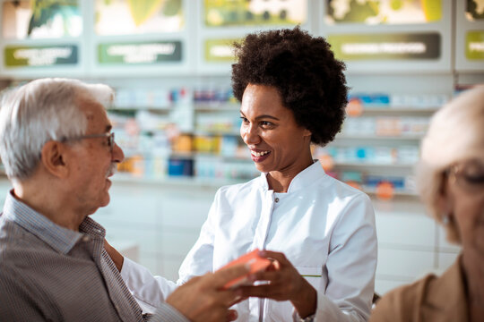 Pharmacist assisting senior couple with medication choice in pharmacy