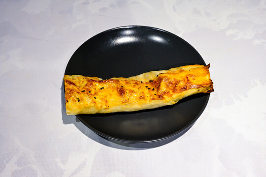 Turkish style meat stuffed filo dough borek served kol boregi.Cheese and minced pie are sliced on a marble background. Turkish name: Kol Boregi, kiymali, peynirli su boregi. Ci borek. Kafkas cig borek