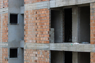 Detail of the construction of a multifamily building in a reinforced concrete structure filled with hollow masonry bricks, showing the door and window openings and sections of the cement mass covering