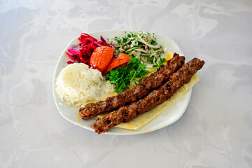 Grilled Turkish Adana, Urfa  Kebab with grilled vegetables, onion and rice on plate. Adana durum, Urfa durum .