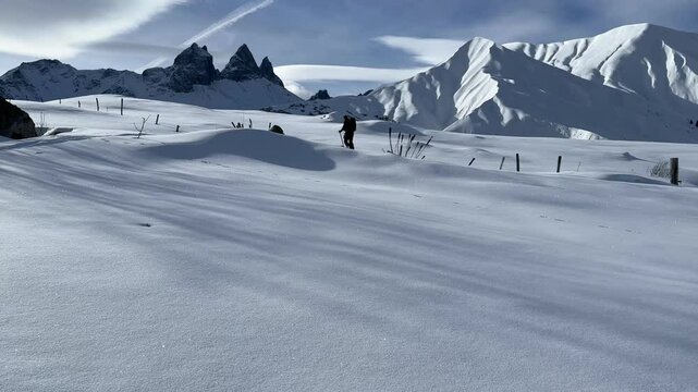 man doing ski touring in front of the aiguilles d'arves; man alone in a winter landscape with fresh snow