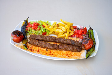 Grilled Turkish Adana, Urfa  Kebab with grilled vegetables, onion and rice on plate. Adana durum, Urfa durum .