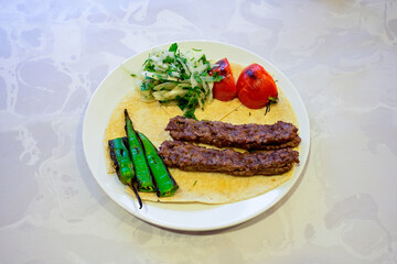 Grilled Turkish Adana, Urfa  Kebab with grilled vegetables, onion and rice on plate. Adana durum, Urfa durum .