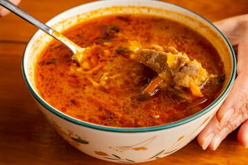 Delicious homemade soup served in a bowl with a spoon on a wooden table