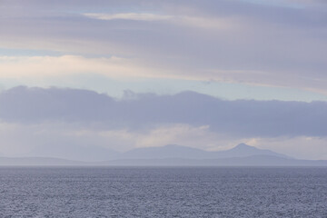 Serene Ocean View with Distant Mountains Under Cloudy Sky