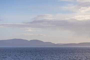 Obraz premium Scenic Ocean View With Distant Hills and Partly Cloudy Sky