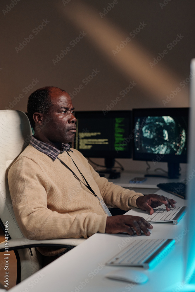 Poster Mature IT support manager decoding data while looking at desktop computer screen and pressing keys on keypad