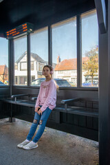 Young girl waiting at a cozy bus stop on a sunny afternoon a charming bus stop, sunlight streaming...