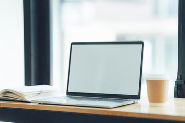 Laptop Mockup on Wooden Desk: Modern workspace with a clean, minimalist aesthetic, featuring a laptop with a blank screen, a notebook, and a coffee cup. Perfect for showcasing your website, app.