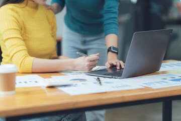 Collaborative Teamwork: A close-up shot of two coworkers, one pointing at a laptop screen while the...