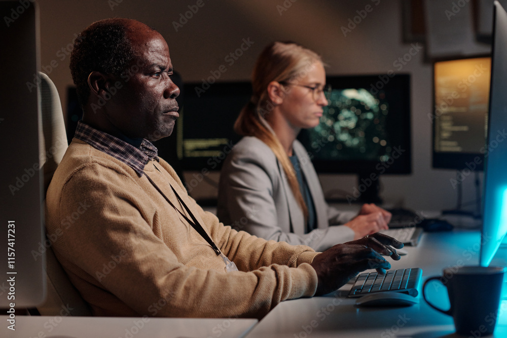 Poster serious african american it engineer looking at computer screen and decoding data while sitting agai