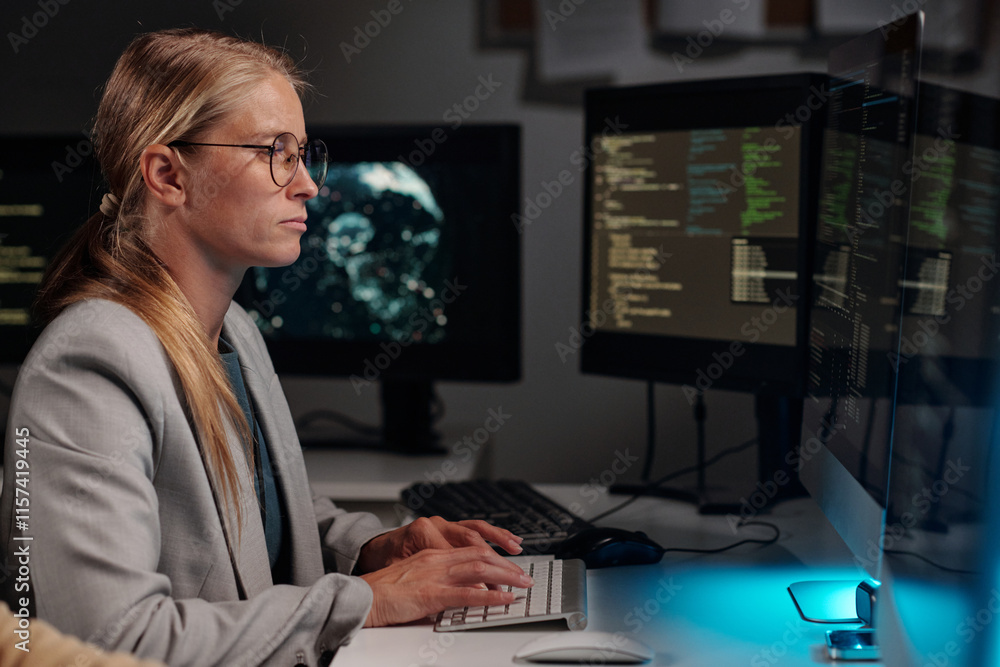 Poster Side view of young serious woman concentrating on solving technical problem or decoding data and typing on computer keypad