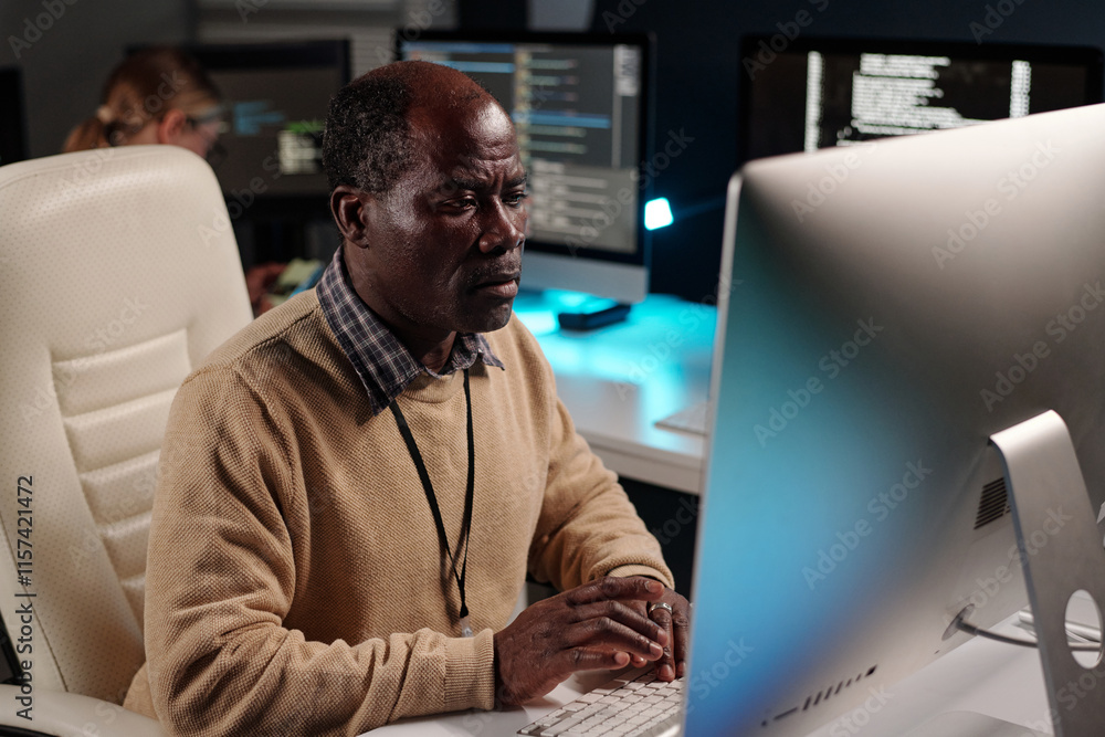 Aufkleber Experienced male IT support manager decoding data while sitting in front of desktop computer monitor and looking at screen