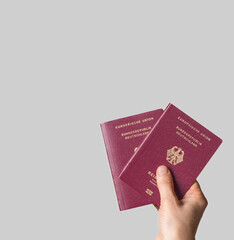 A close-up shot of a hand holding three German passports, against a clean white background with ample copy space, symbolizing travel and family mobility.
