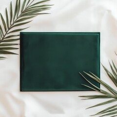 Emerald Green Mockup: A sleek, emerald green card or invitation sits amidst lush palm leaves on a soft, white fabric, creating a minimalist and elegant backdrop for your design.
