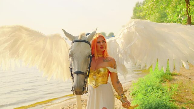 Art video real people Fantasy woman warrior queen hand touching white horse with wings pegasus animal. Greek style goddess girl sexy face elf holds magic sword. summer nature bright sun sky green tree
