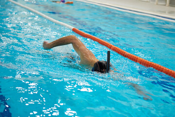 A man is crawling in a pool with a snorkel.