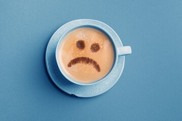 Upset face on coffee foam. Blue Monday.