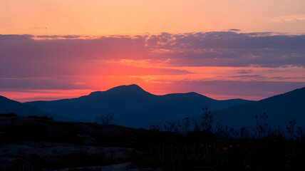 Fototapeta premium A photo of a sunset in the mountains. The sky is painted with shades of orange, pink, and purple.