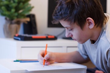 A student solves math problems on a computer. a teenage boy is studying online