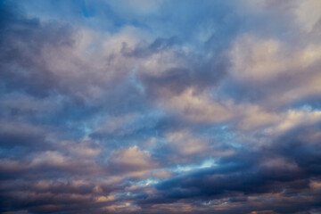 Bright sunlight illuminates gray winter clouds in a blue sky