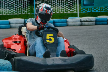 A racer in a helmet driving a rental go-kart on the track, participating in go-karting, go-kart...